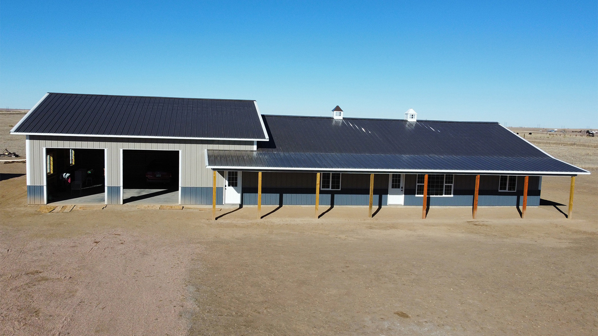 Blue and gray barndominium featuring two garage doors and front awning